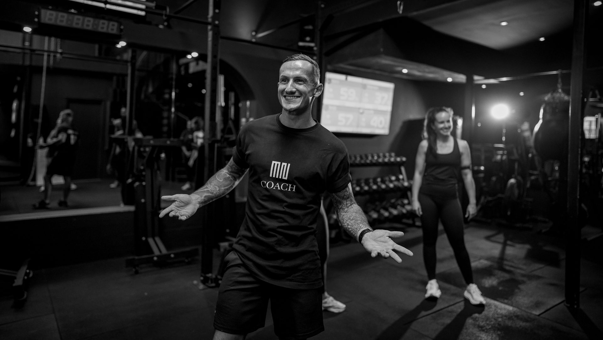 Un coach MONT NOIR souriant, bras ouverts, pendant une séance au club Savanna